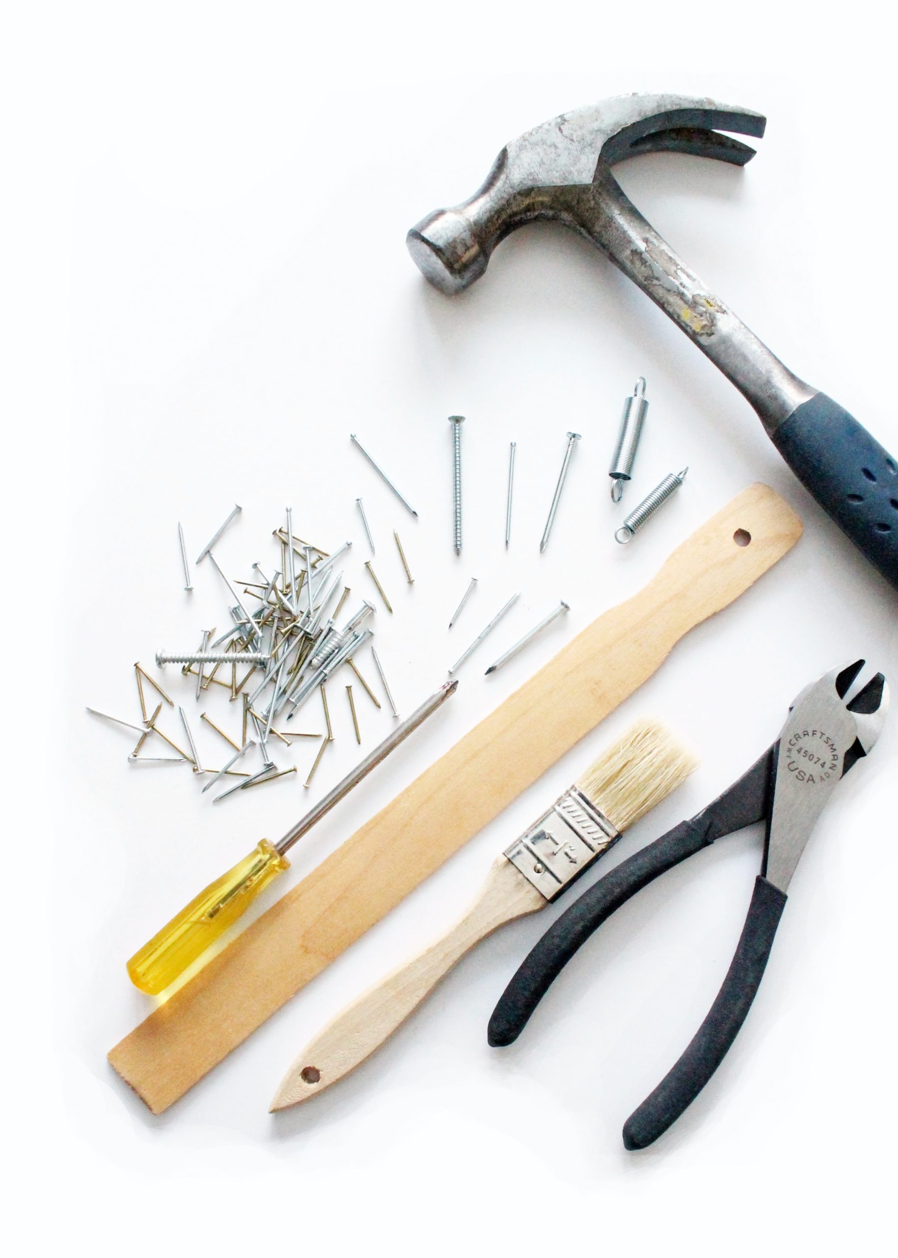 Hammer, Schraubendreher, Nägel und weiteres Werkzeug auf weißer Fläche